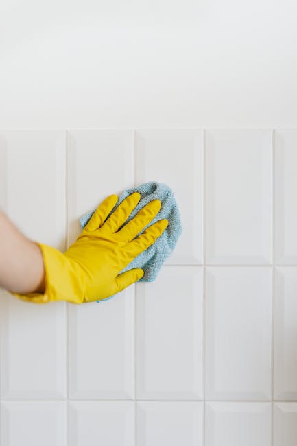 A person wearing brown cleaning gloves is adjusting a lit-up sign board displaying the words 'CLEANING HOME' in black letters on a white background, indicating domestic cleaning services. The sign is